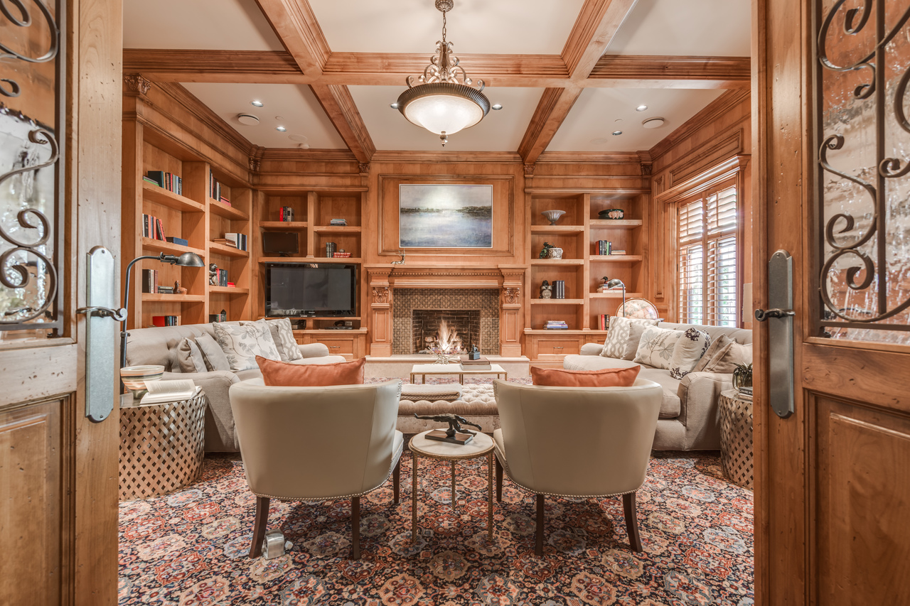 Wood-paneled living room with a fireplace, sofas, armchairs, and built-in bookshelves—perfect for relaxing after a day exploring Vancouver, British Columbia.