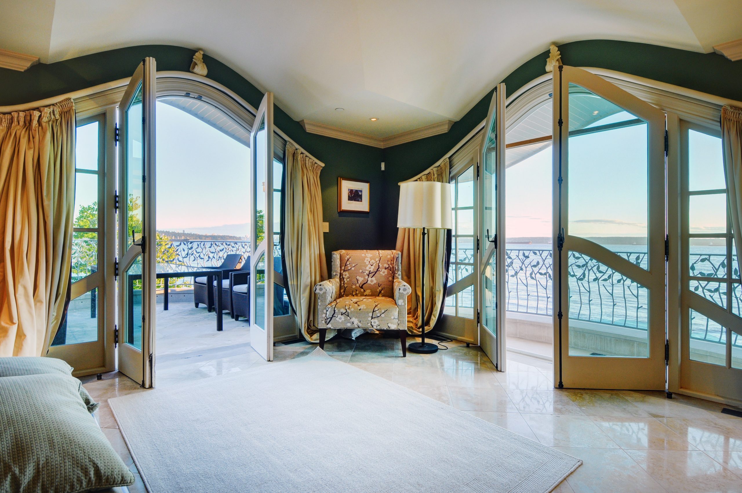 Room with quality architecture, featuring open French doors to a balcony that overlooks water and Vancouvers scenic outdoor view at sunset.