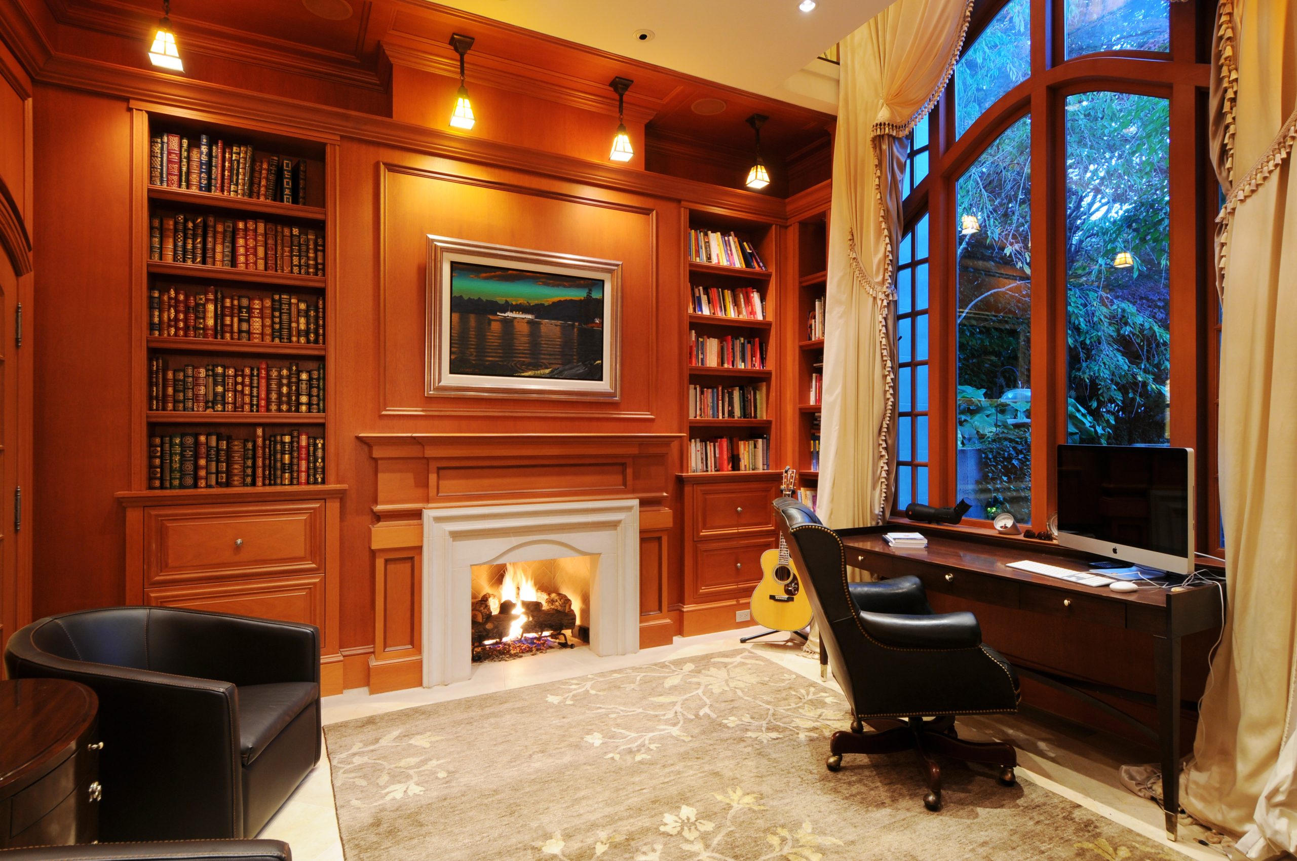 Elegant home office with wood paneling, built-in bookshelves, fireplace, desk, and large window overlooking greenery—crafted by a skilled general contractor in Vancouver.