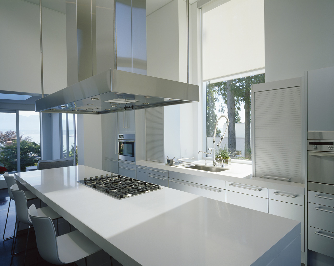 Kitchen by a Vancouver general contractor featuring white cabinets, island, gas cooktop, and large windows that let in abundant natural light.