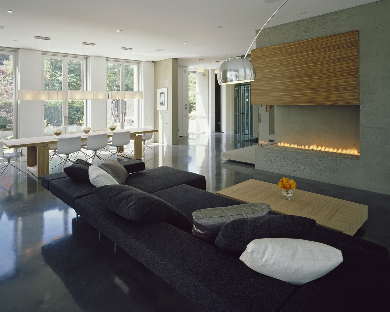 Vancouver living room with a quality black sofa, wooden fireplace, dining table, and large windows letting in natural light.