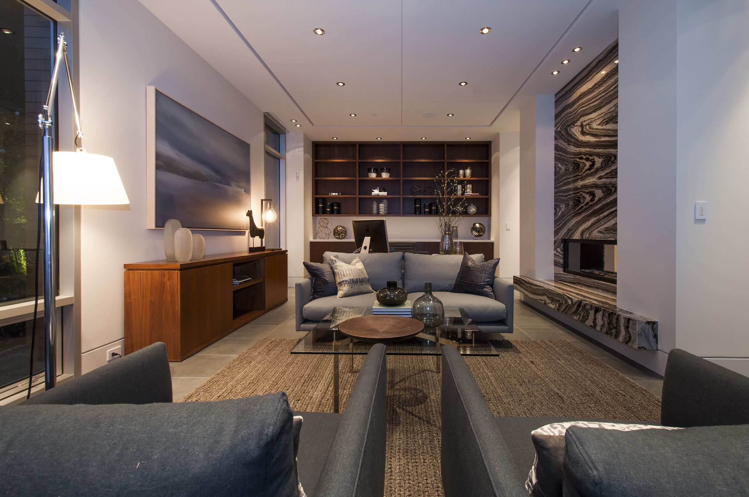 Room with dark sofas, a round coffee table, art on the wall, and built-in shelves—crafted with quality materials by a reputable company in British Columbia.